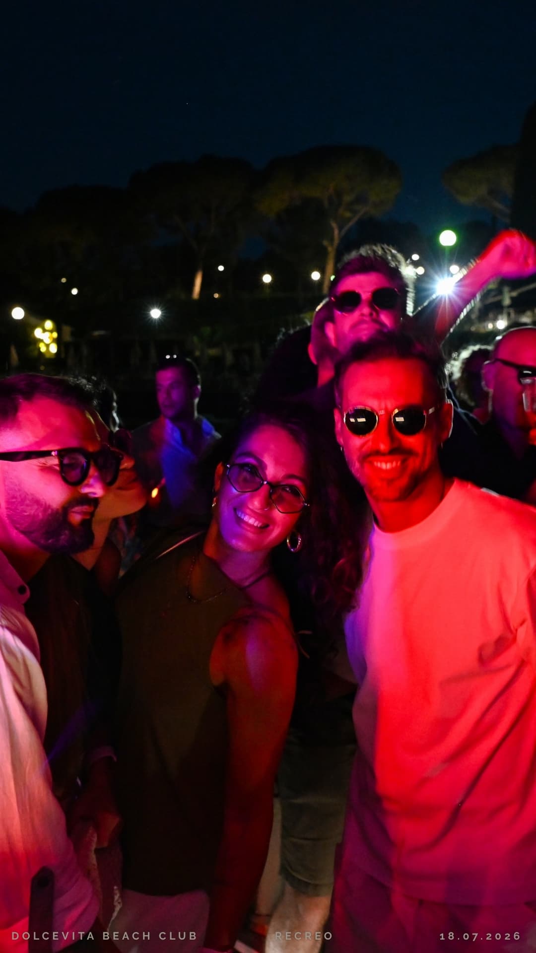 Amici sorridono in posa tra le luci rosa
