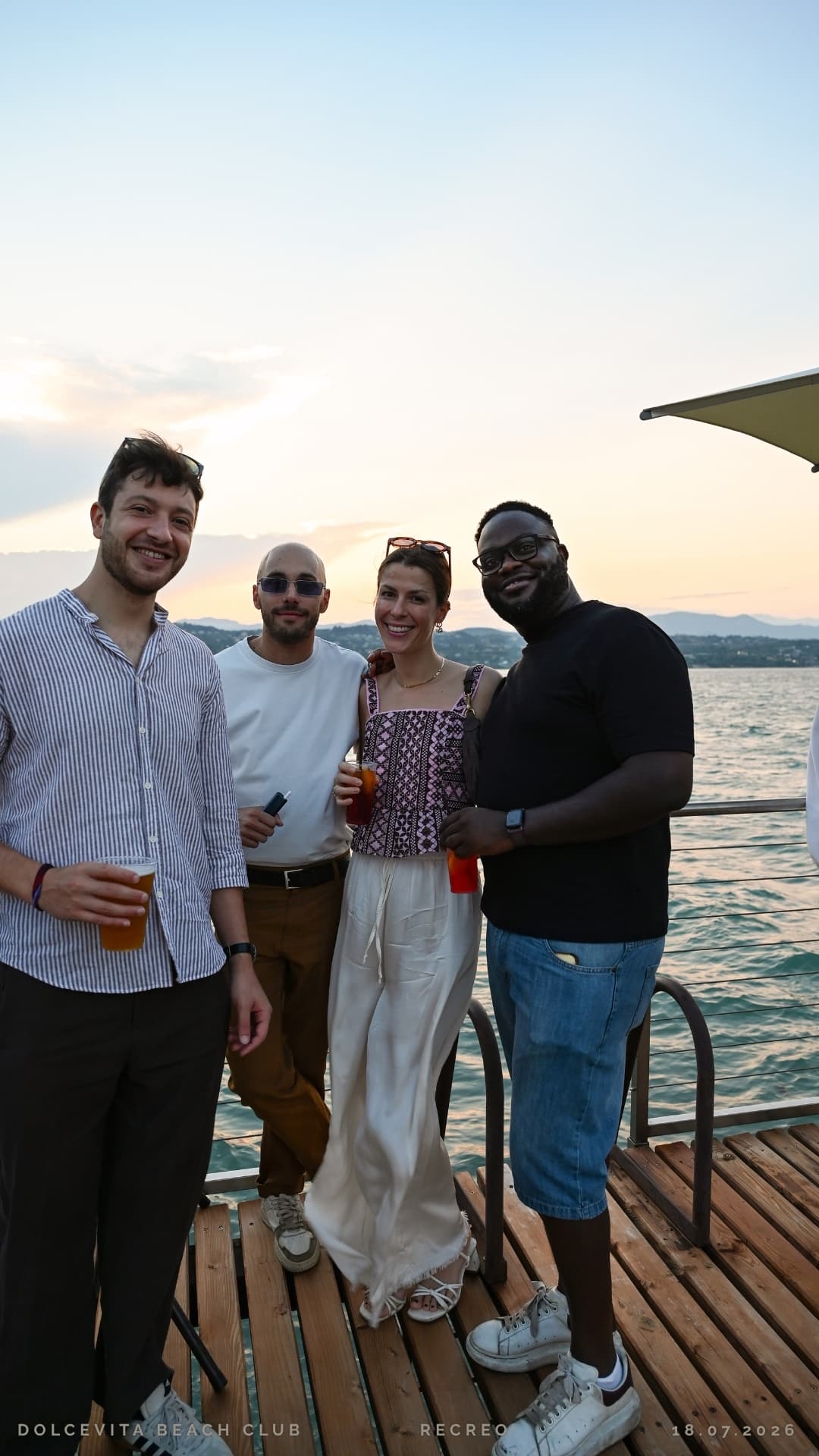 Gruppo di amici posa con i drink sul pontile
