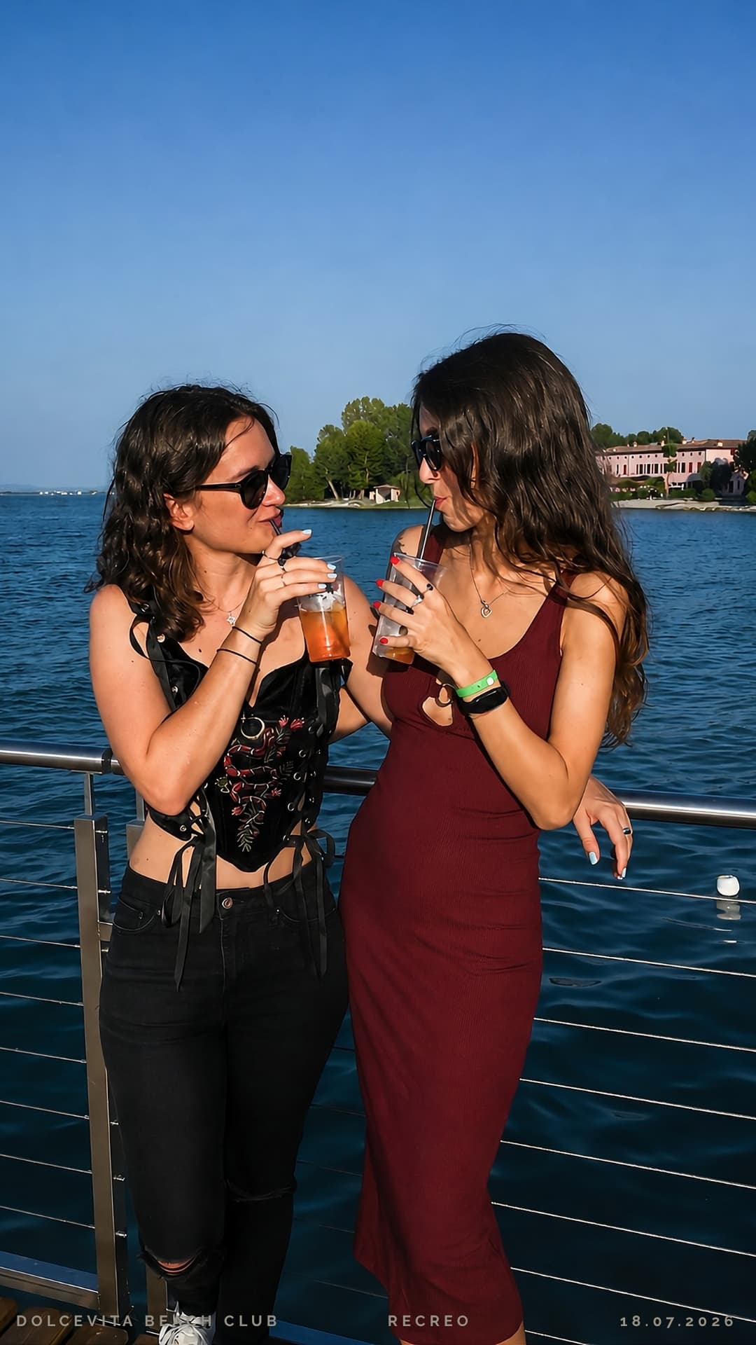 Due amiche brindano con i drink al sole sul pontile