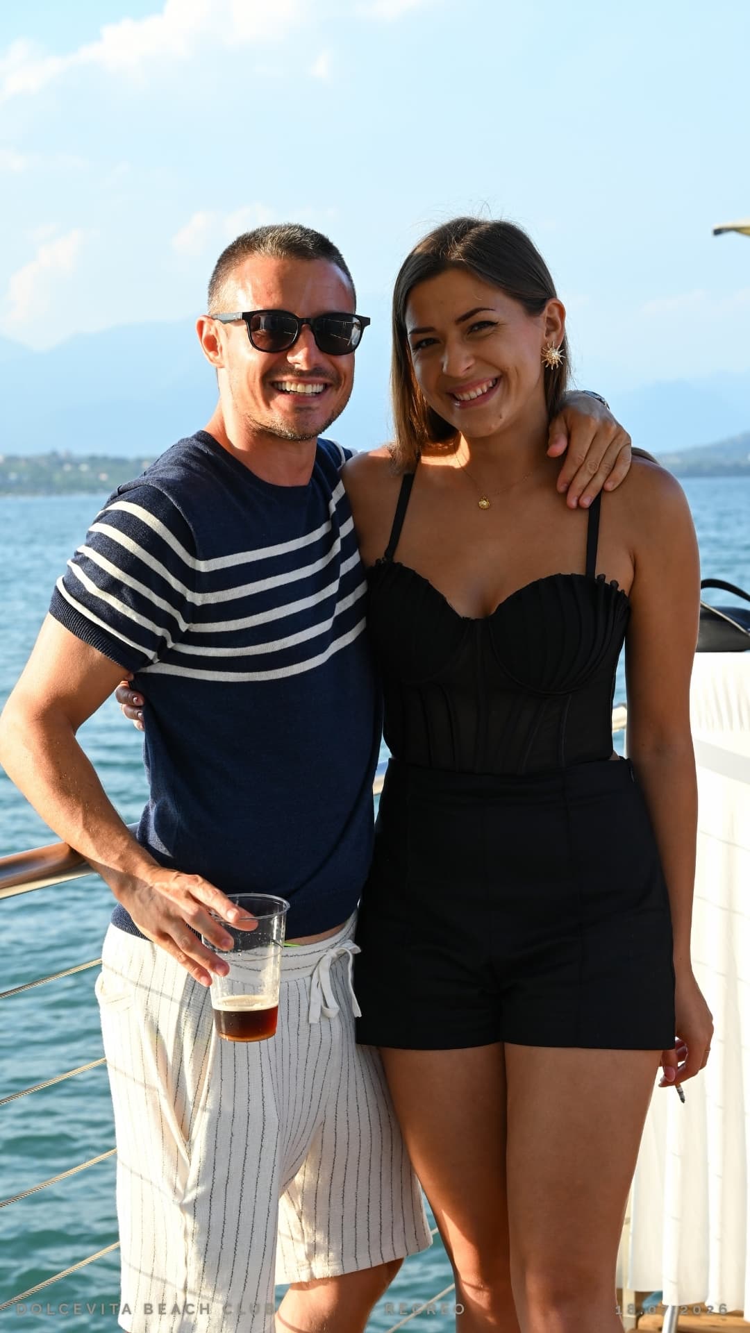 Coppia sorridente con drink davanti al lago