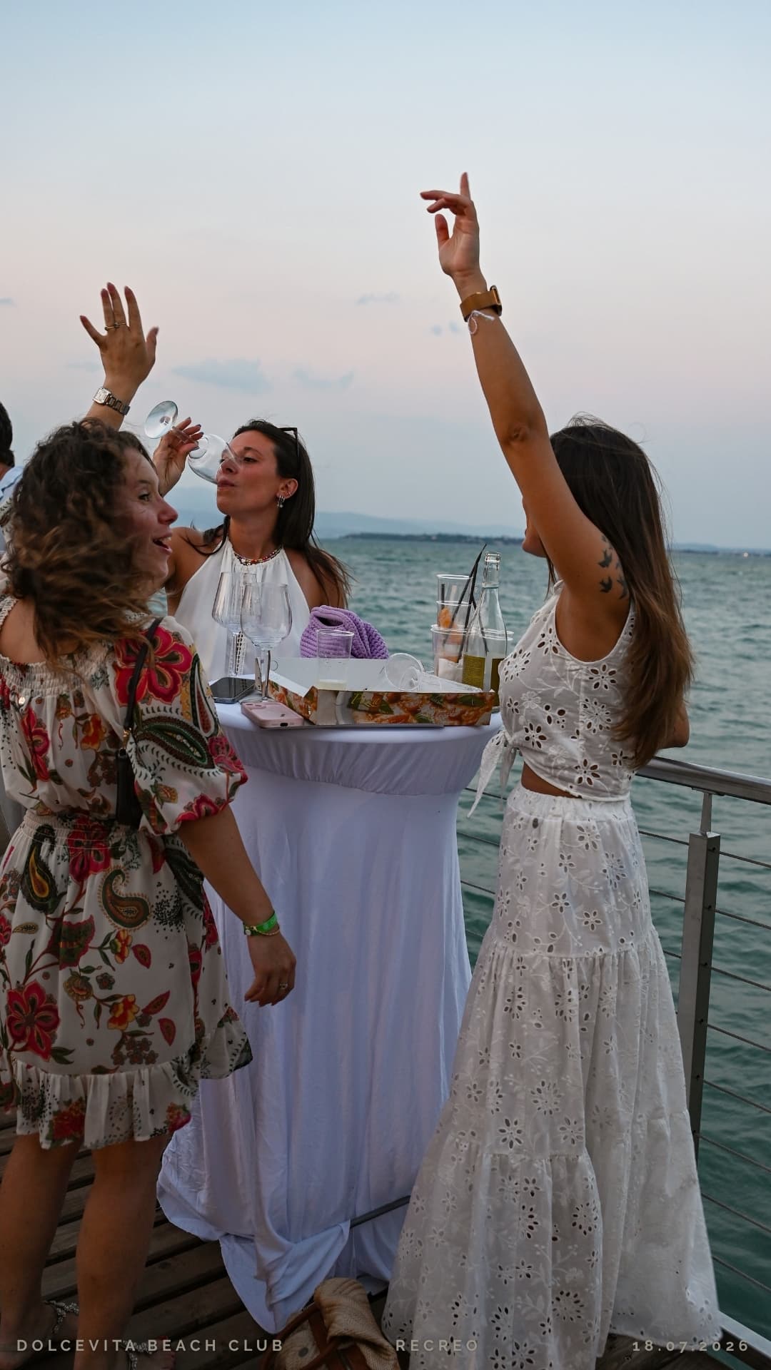 Amiche brindano con le braccia alzate al tramonto