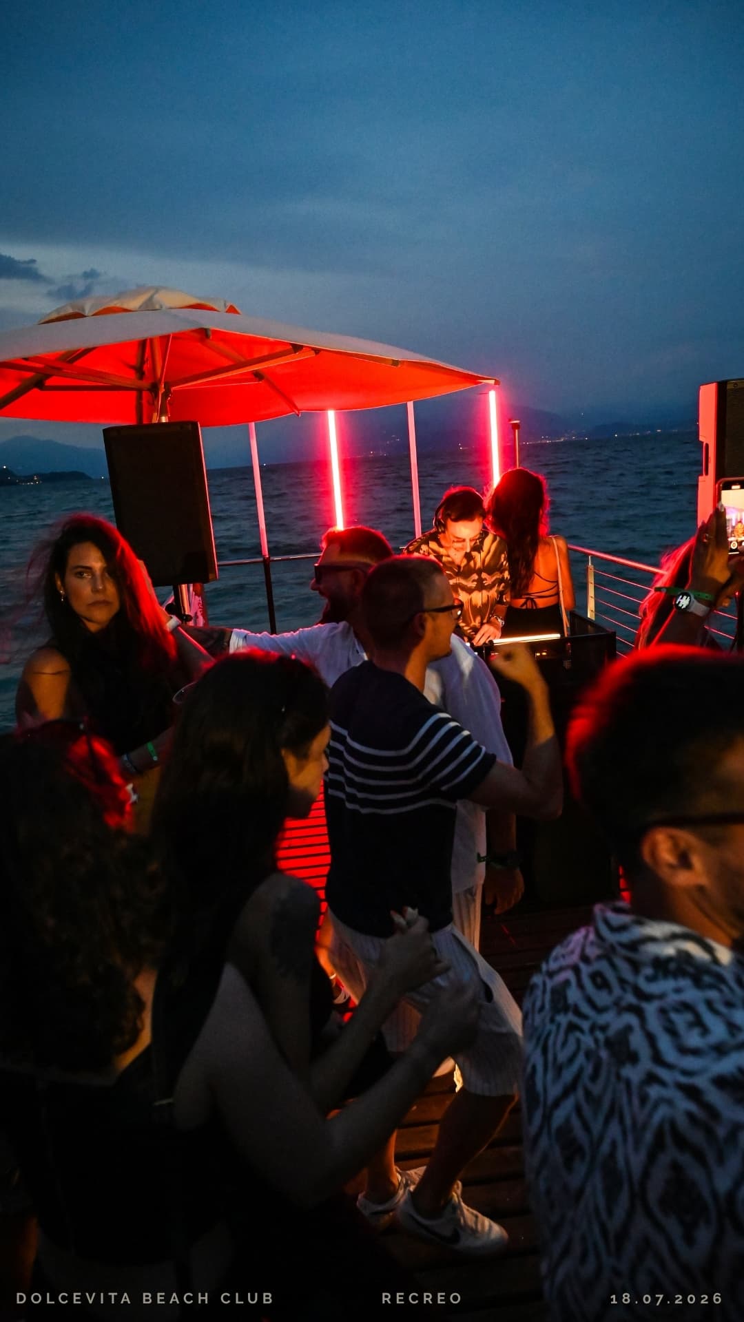 Serata sul pontile con luci rosse e dj in consolle