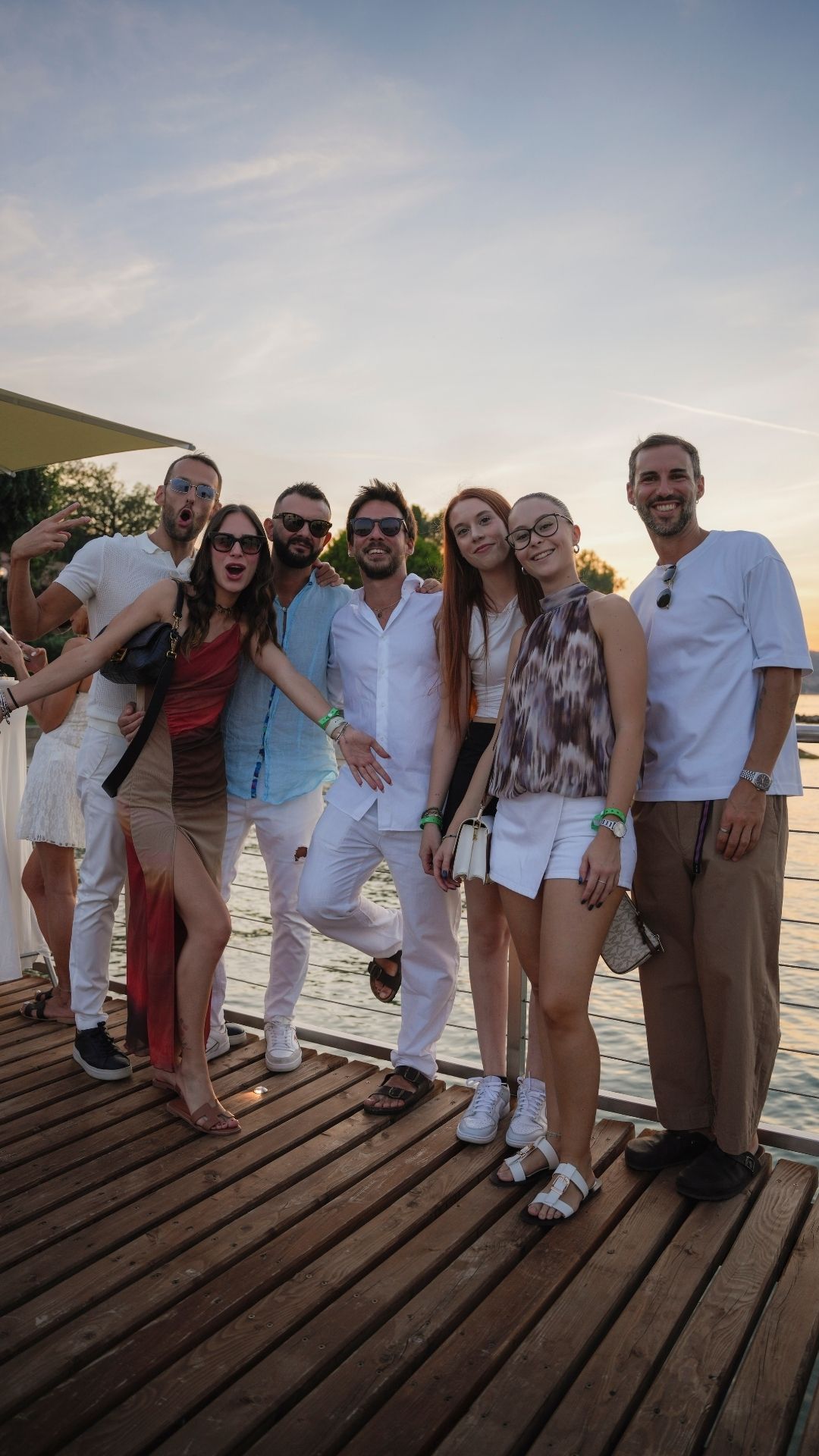 Gruppo di amici festeggia sul pontile al tramonto