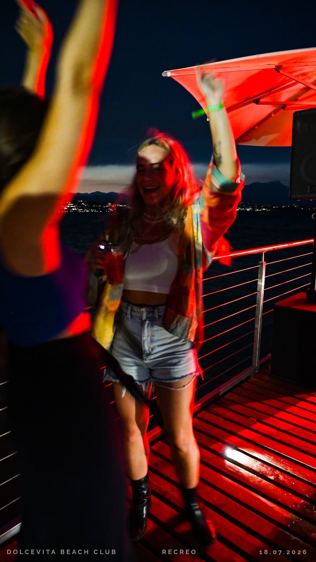 Ragazza balla con drink sul pontile