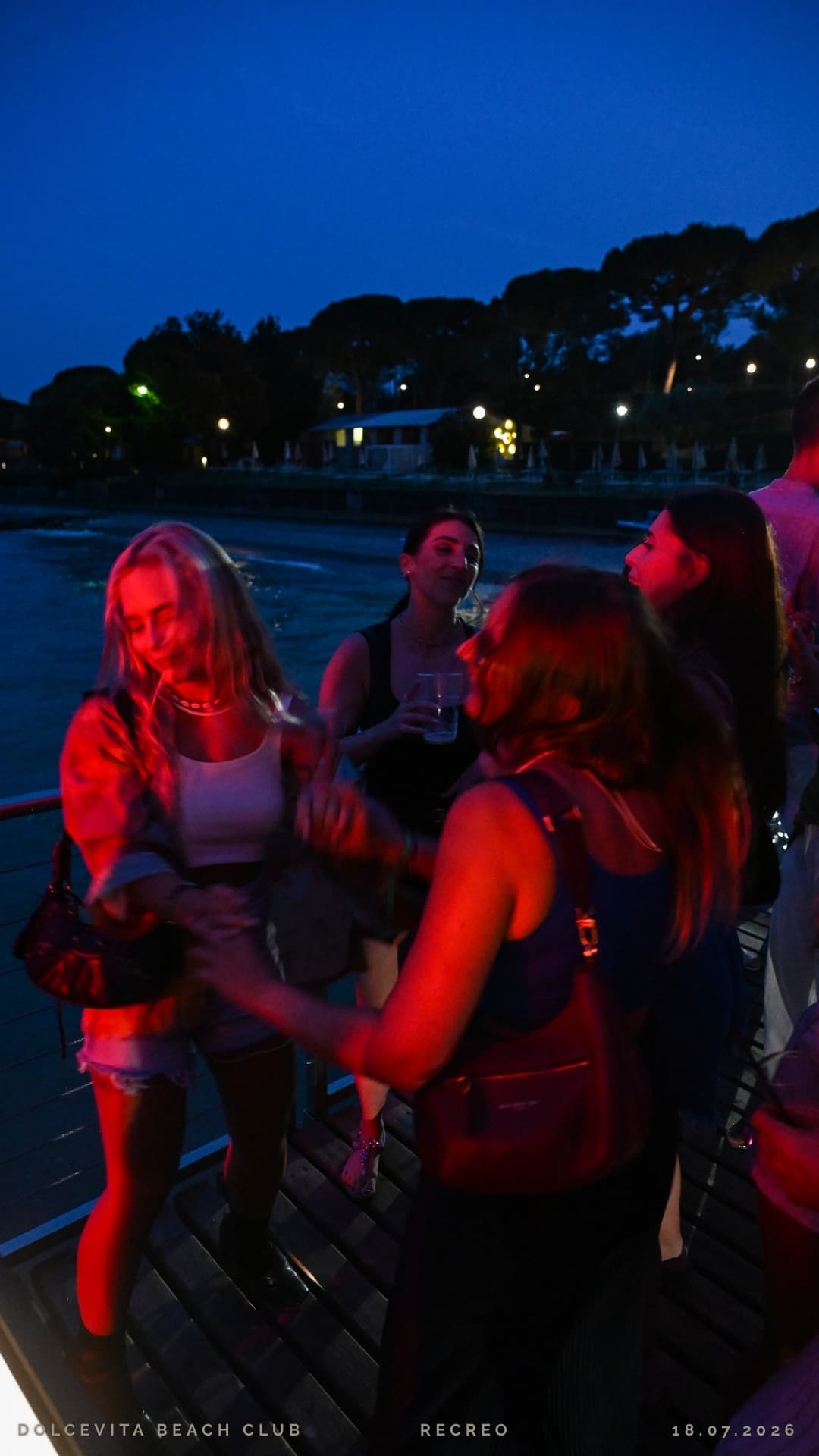 Amiche che ballano sul pontile con luci rosse