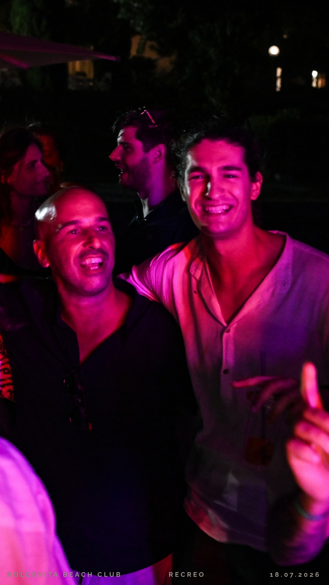 Due amici sorridenti tra luci fucsia