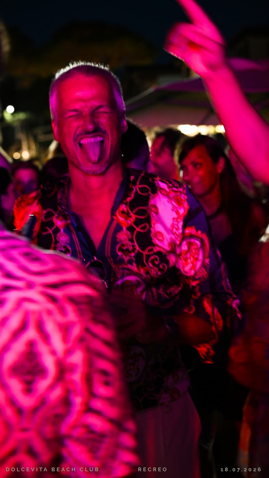 Ospite scherza in camicia fantasia tra le luci fucsia