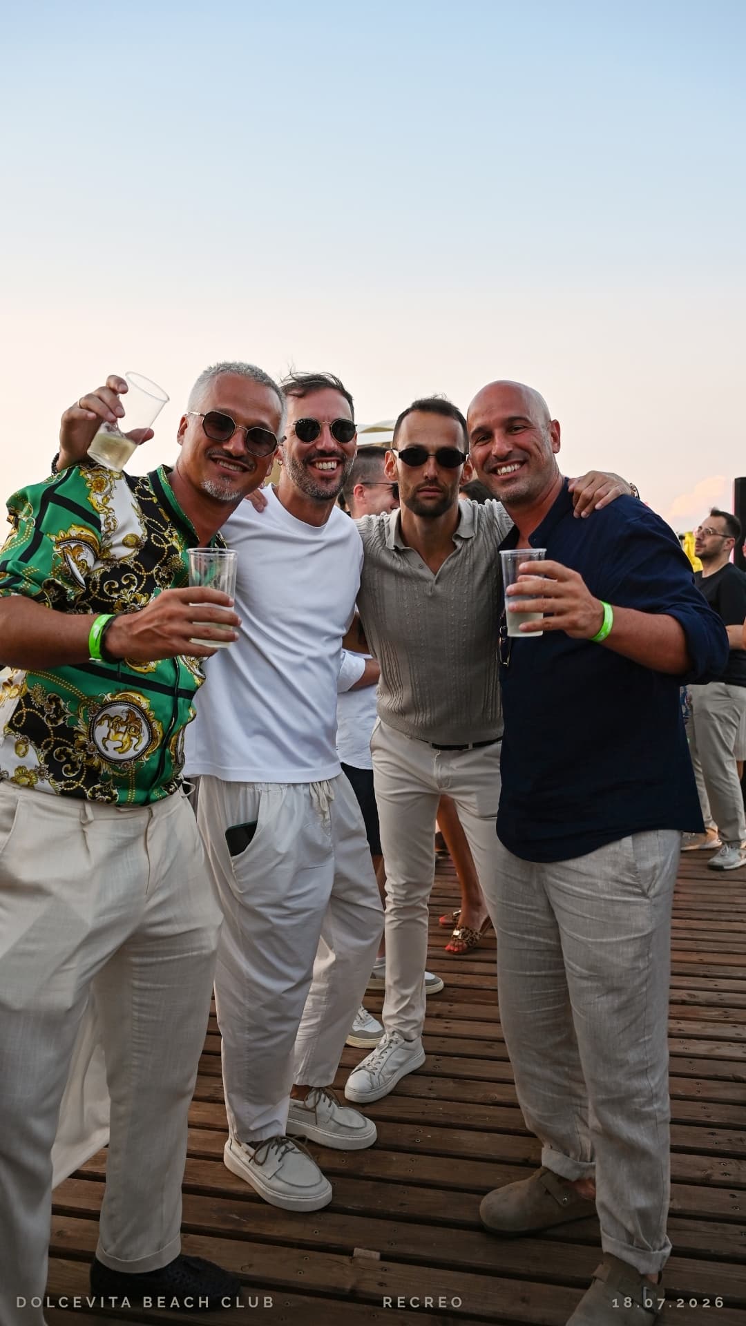 Quattro amici in posa con i drink sul pontile