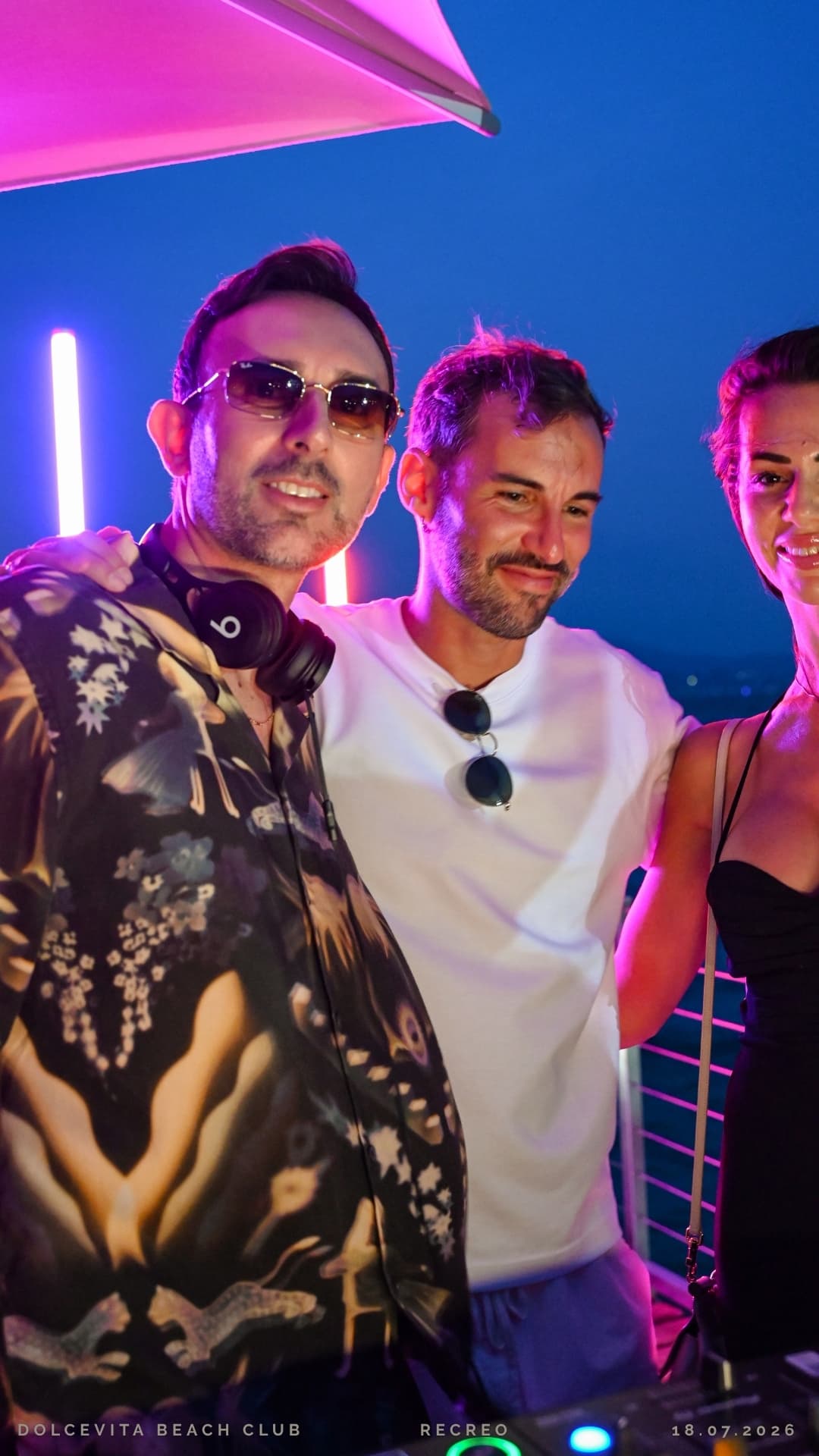 Dj con cuffie e amici in posa tra le luci rosa