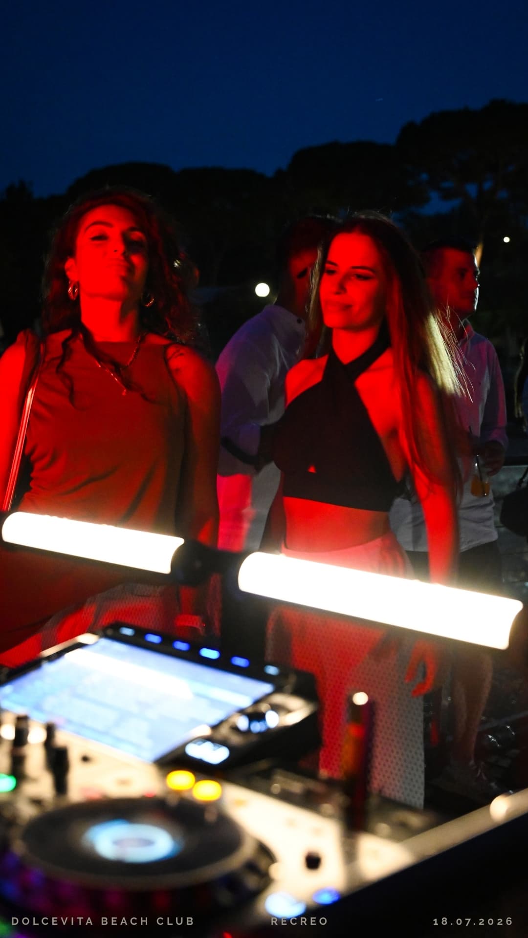Due ragazze davanti al dj set illuminate di rosso
