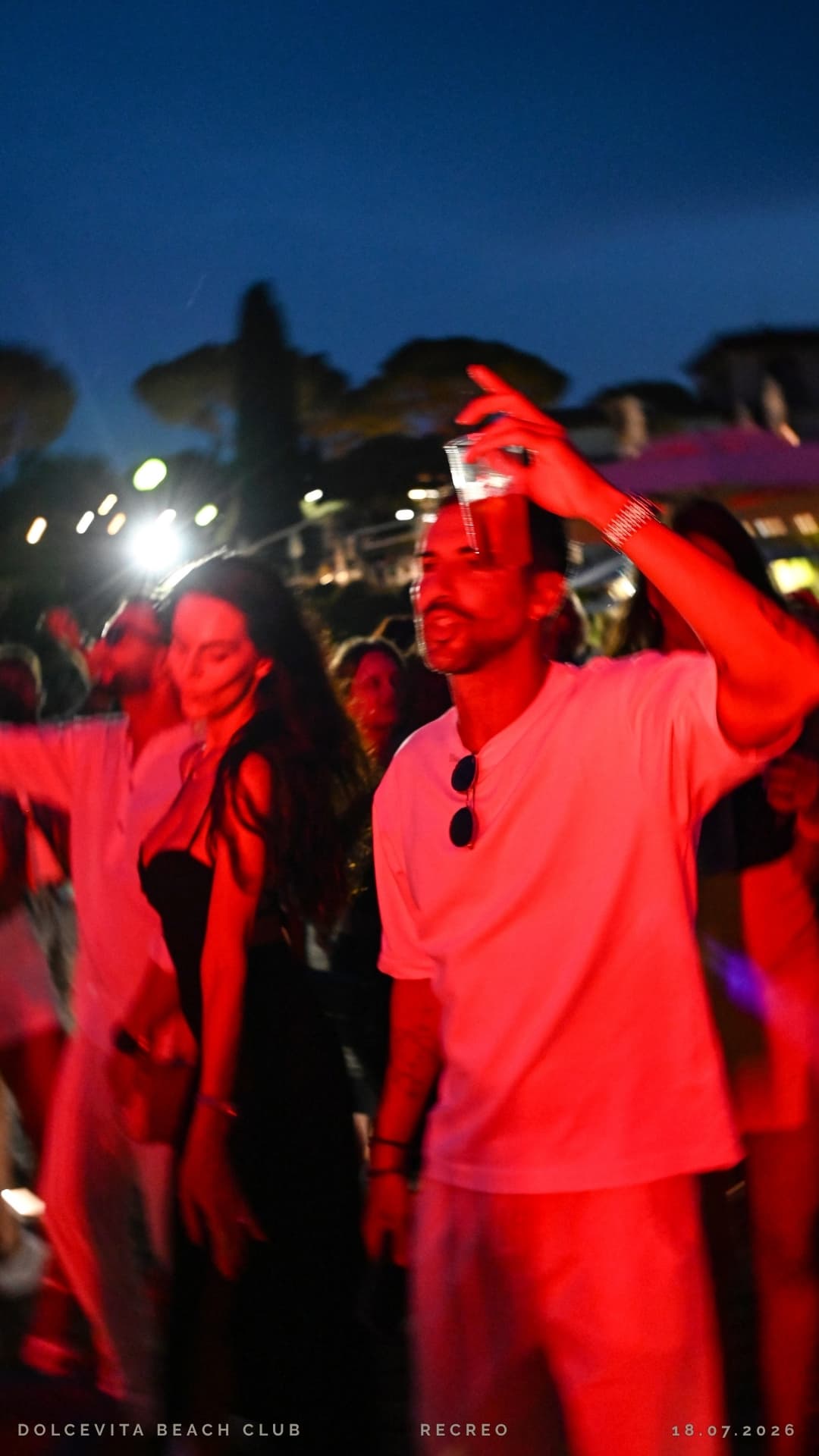 Ospite balla con bicchiere alzato tra le luci rosse