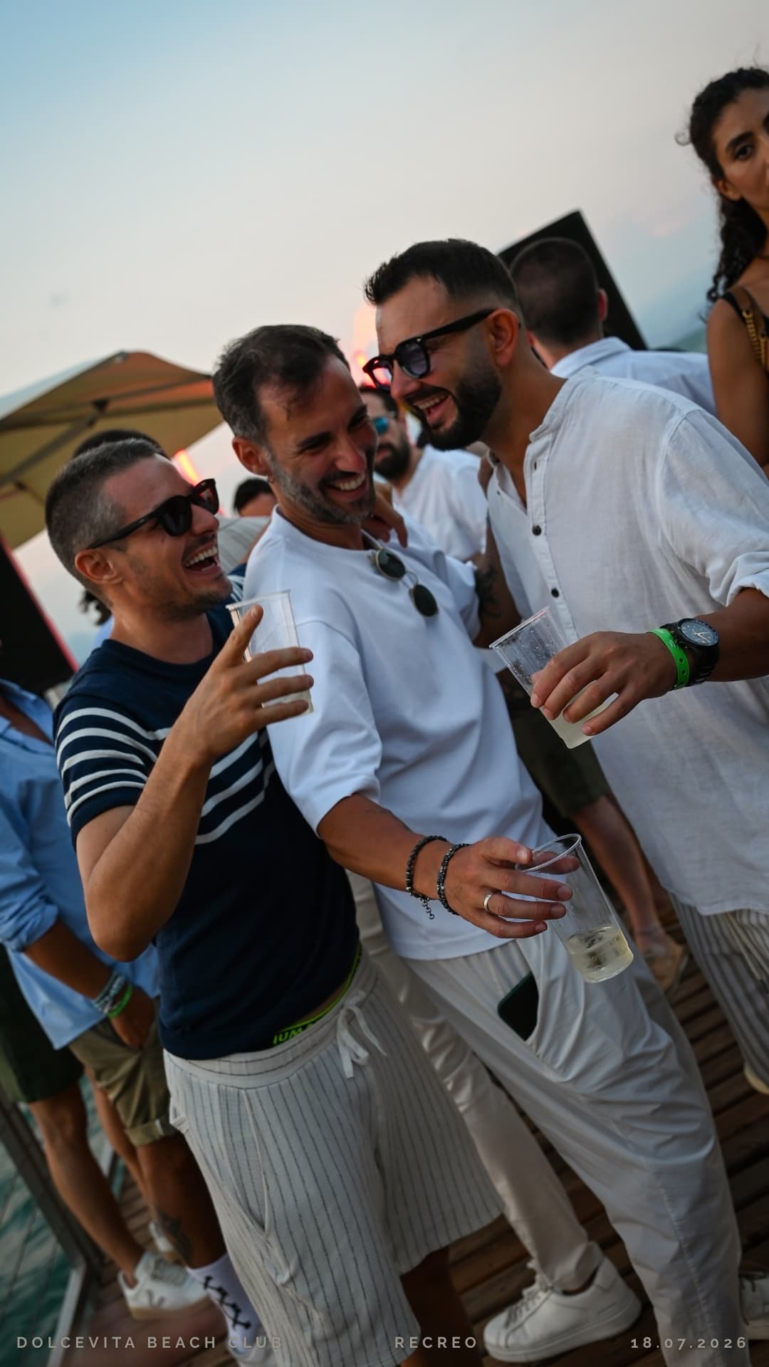Amici ridono insieme con i drink al tramonto