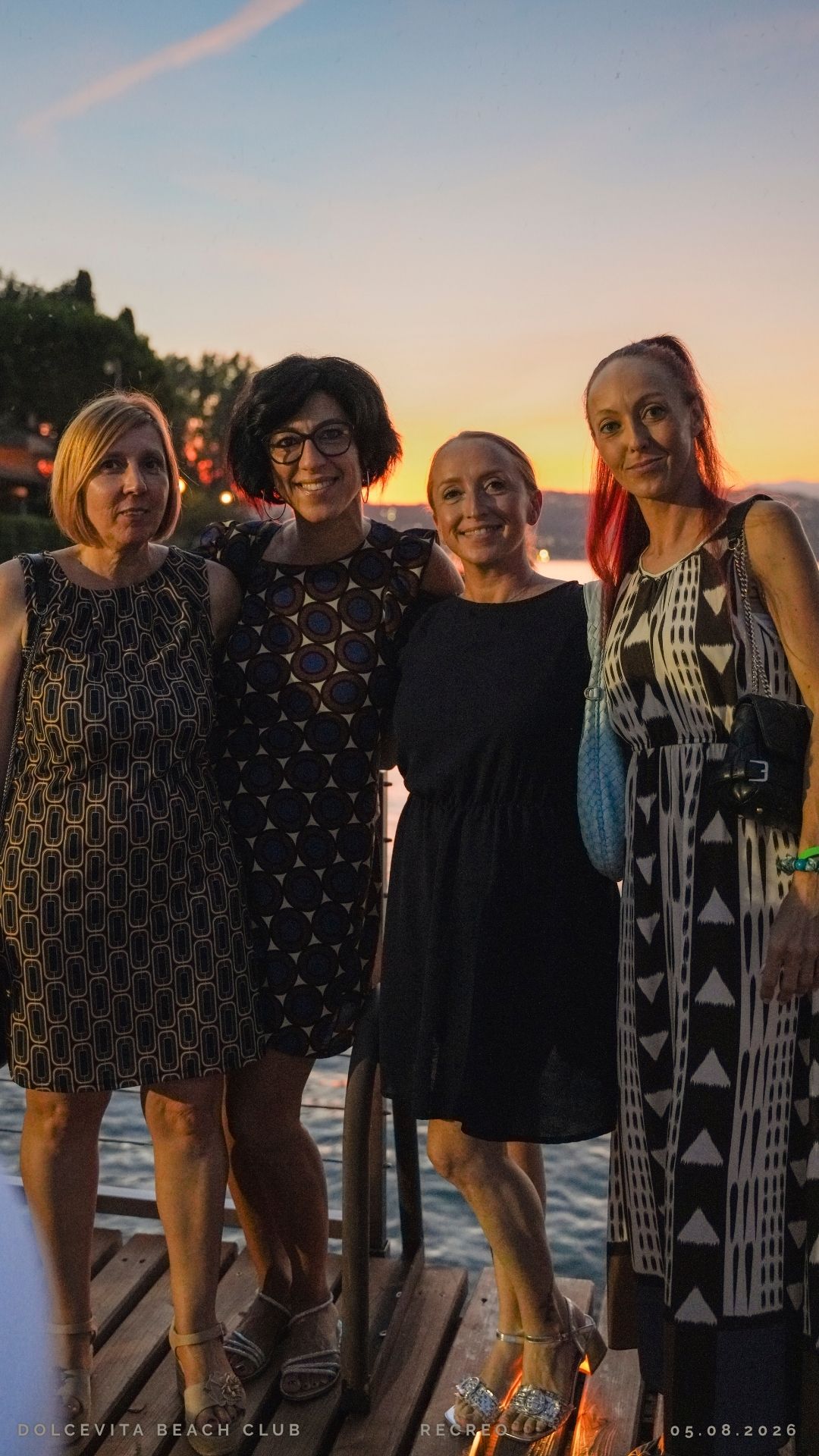 Quattro amiche posano sul pontile al tramonto