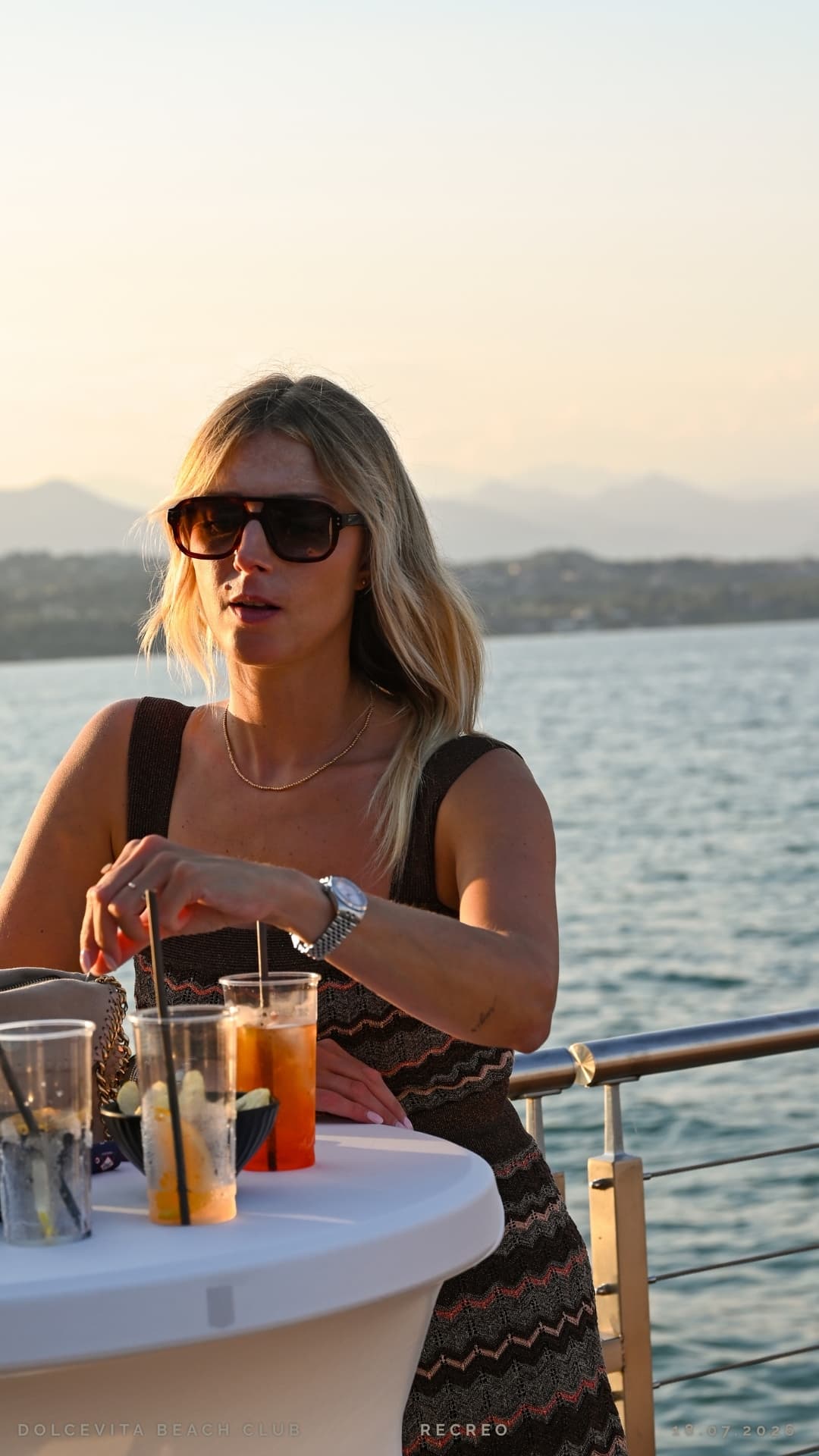 Ospite con cocktail al tramonto sul lago