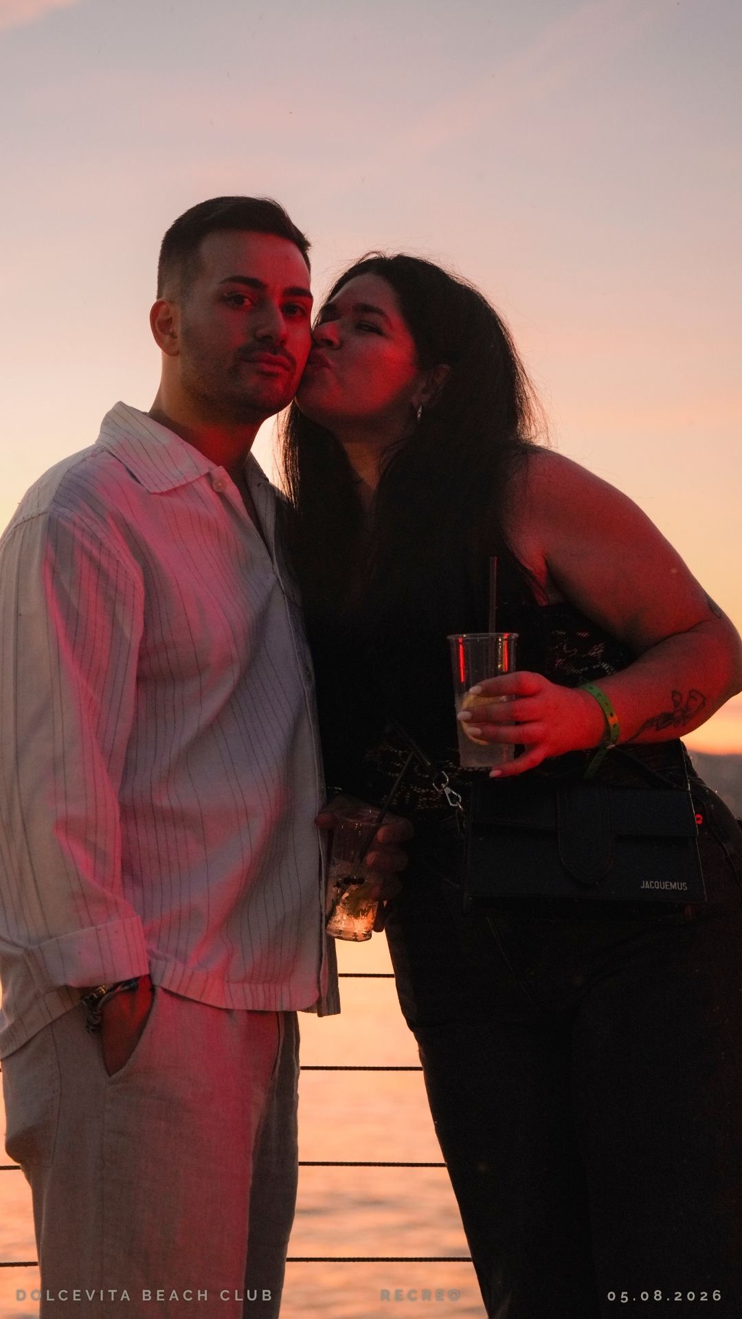 Coppia posa con drink al tramonto