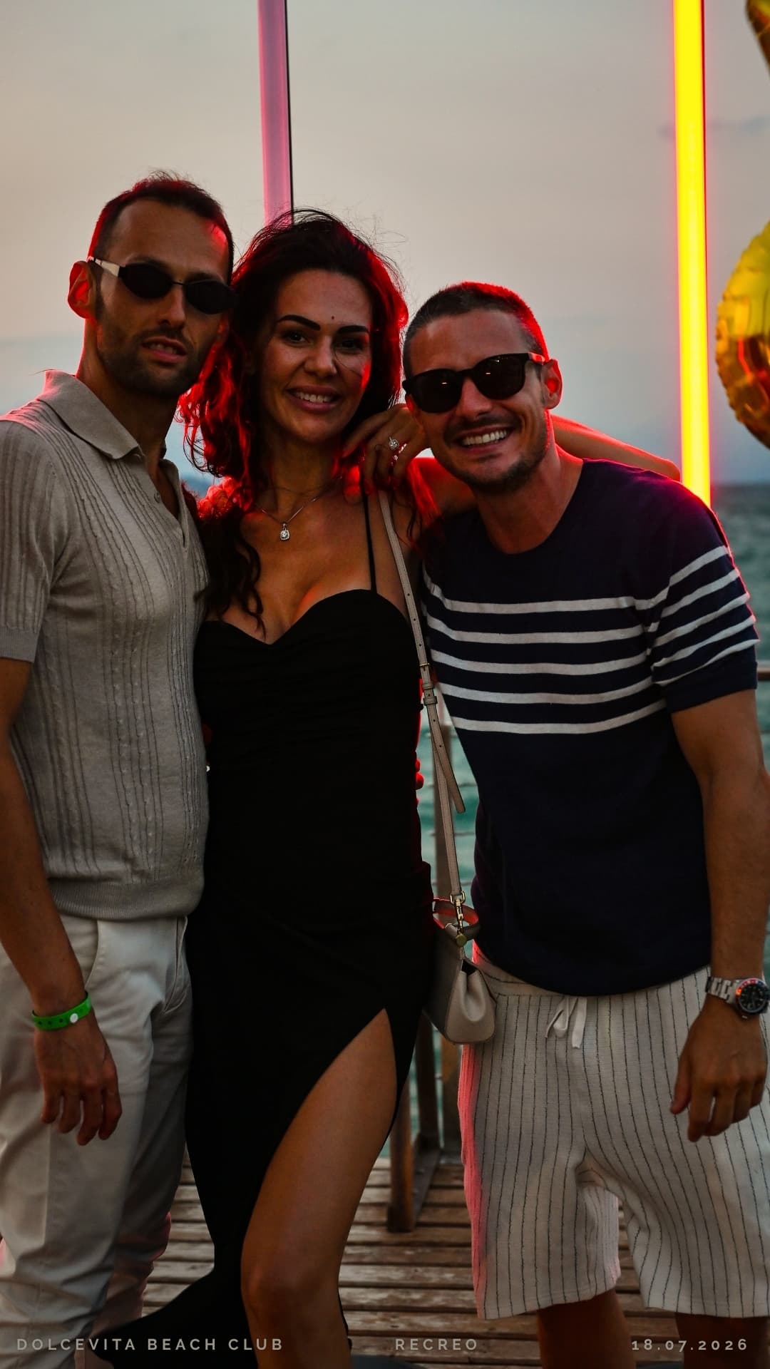 Tre amici in posa con le luci rosse sullo sfondo