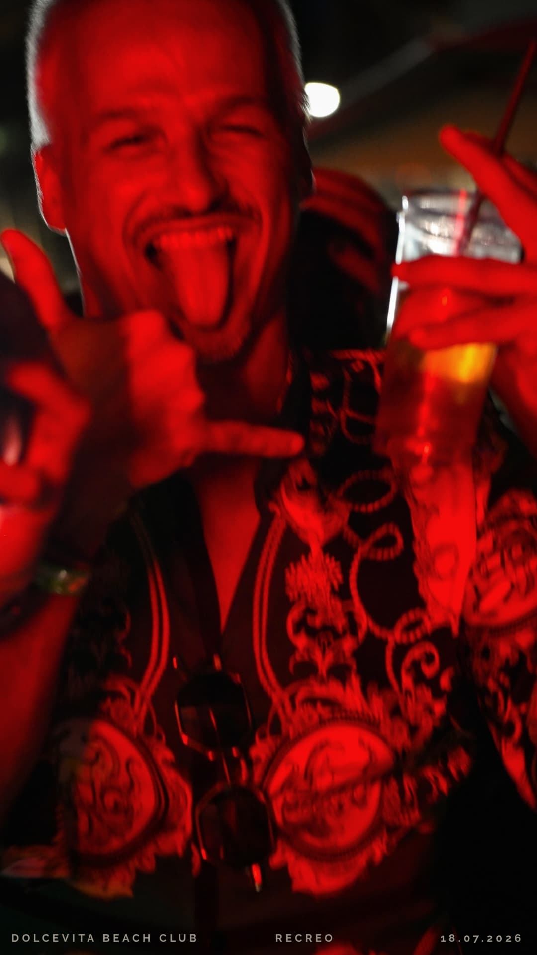 Ospite sorridente fa il segno rock con il drink
