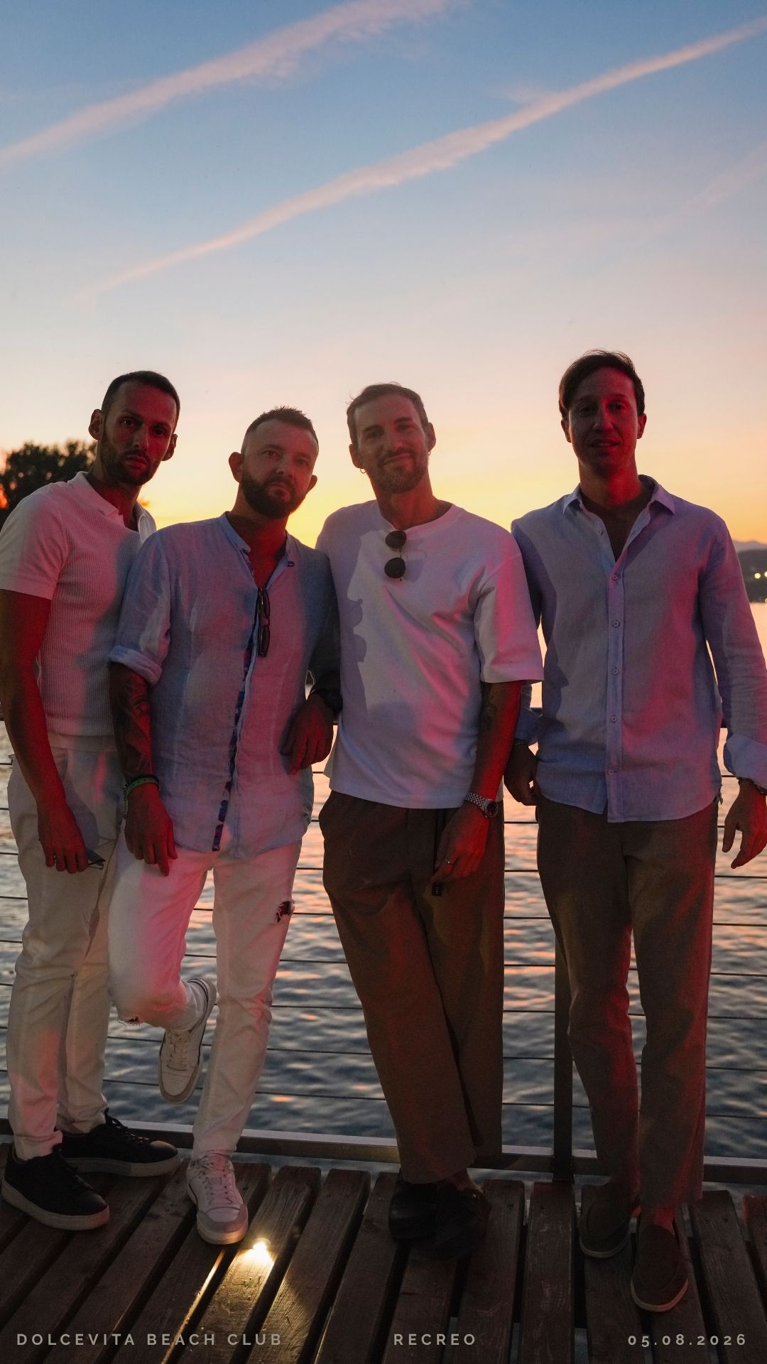 Quattro amici posano sul pontile al tramonto
