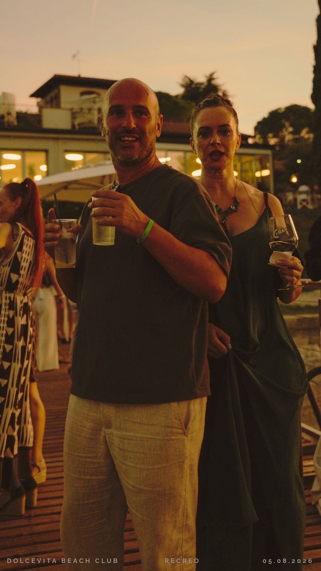Coppia con drink al crepuscolo sul pontile