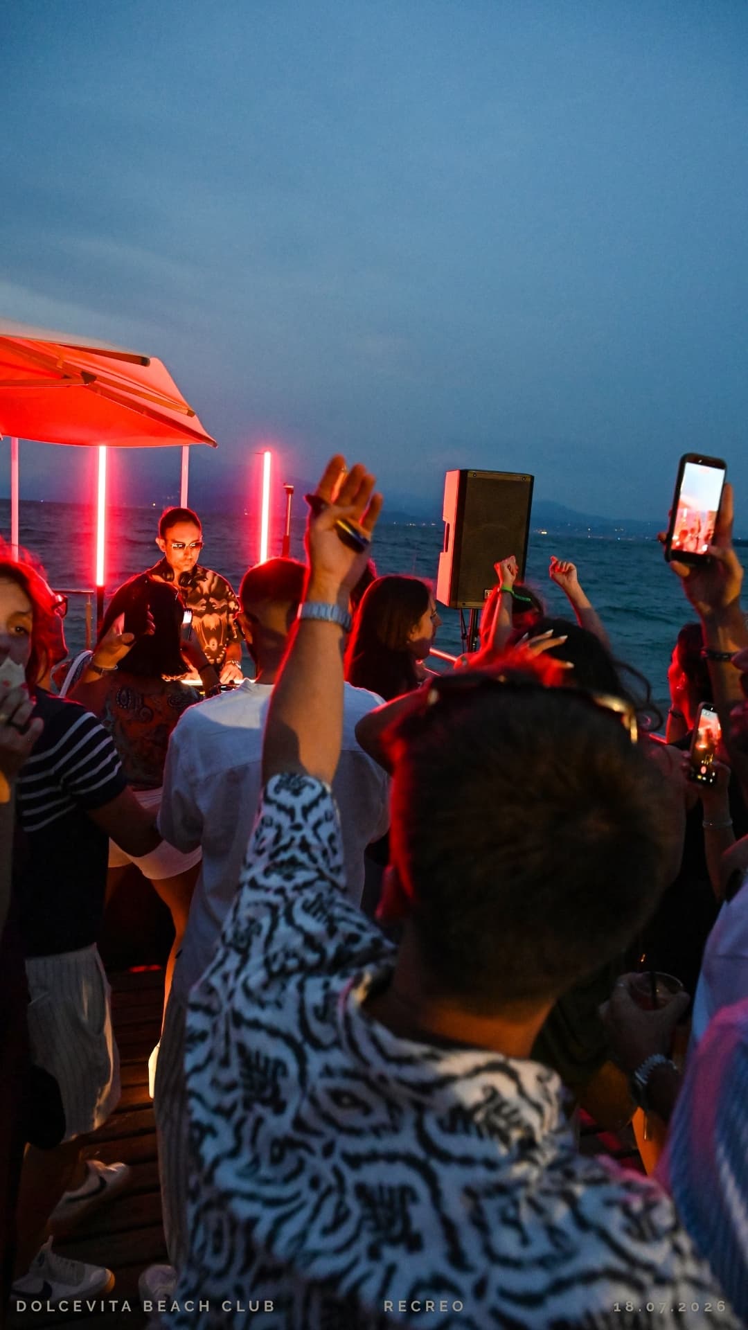Pubblico con le mani alzate davanti al dj set sul lago