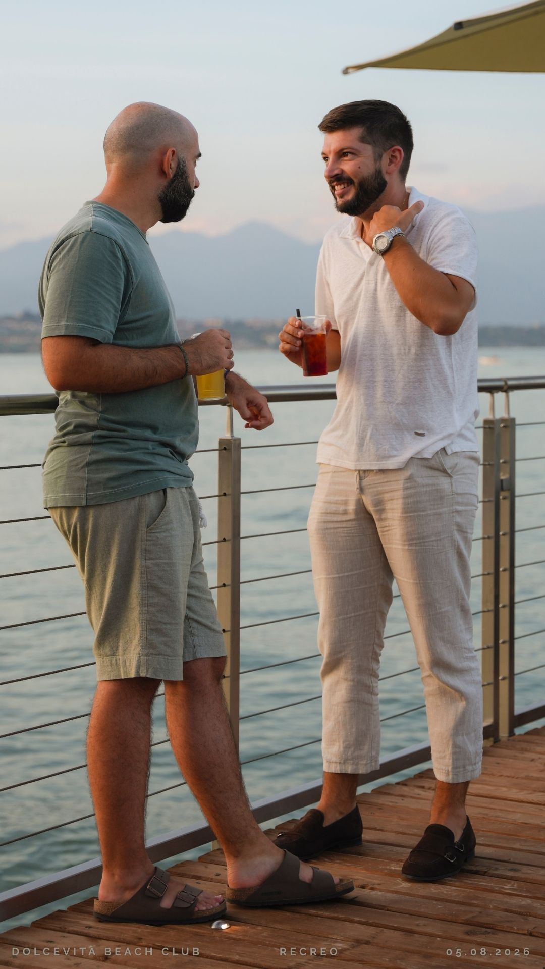 Due amici conversano con drink sul pontile